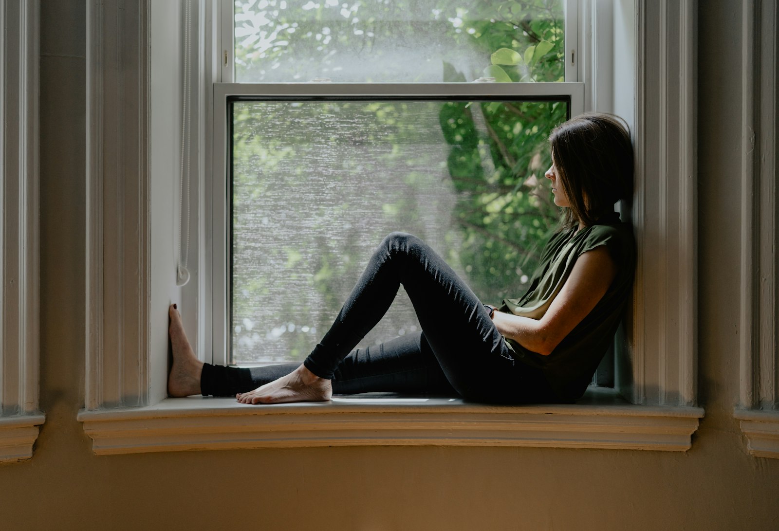Mujer sentada junto a una ventana: psicólogo para la depresión en León